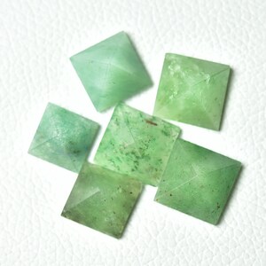 Peut inclure: Six pyramides en pierre précieuse verte, chacune avec une base carrée et un sommet pointu. Les pyramides sont faites d'un matériau vert translucide avec une apparence légèrement nuageuse. Elles sont disposées en un groupe lâche sur une surface blanche.