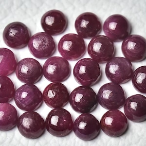Könnte beinhalten: Eine Sammlung von 25 runden, cabochon geschliffenen Rubinen. Die Rubine sind tiefrot und haben eine glatte, polierte Oberfläche.