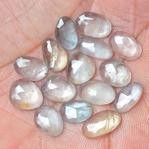 Puede incluir: Una colecci&oacute;n de 14 piedras preciosas ovaladas facetadas, transl&uacute;cidas, de color azul claro. Las piedras tienen una apariencia ligeramente nublada y est&aacute;n dispuestas en un mont&oacute;n suelto.