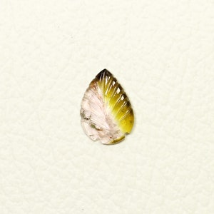 May include: A teardrop-shaped carved gemstone pendant with a pink and green color gradient. The gemstone is carved to resemble a leaf with a detailed vein pattern.