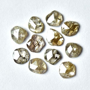 May include: A collection of twelve rough, faceted, and translucent brown diamonds. The diamonds are irregularly shaped and have a variety of sizes.
