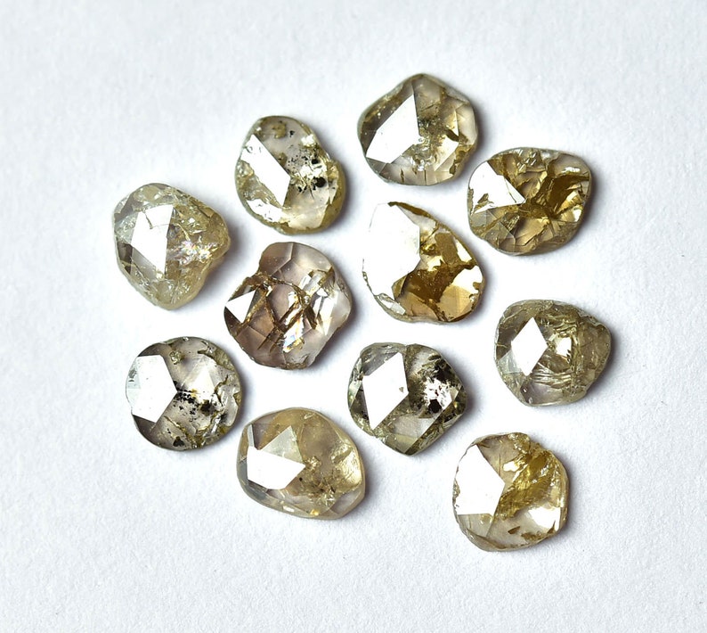 May include: A collection of twelve rough, faceted, and translucent brown diamonds. The diamonds are irregularly shaped and have a variety of sizes.