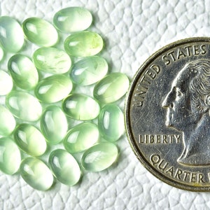 May include: A collection of 25 oval-shaped green gemstones, each approximately the size of a US quarter.