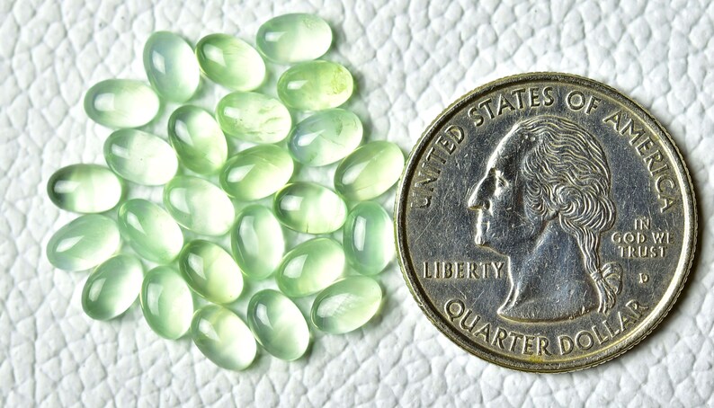 May include: A collection of 25 oval-shaped green gemstones, each approximately the size of a US quarter.