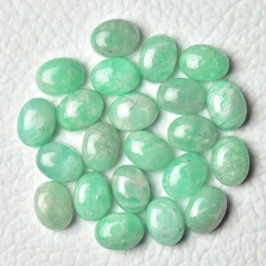 Peut inclure: Une collection de 20 pierres pr&eacute;cieuses vertes de forme ovale. Les pierres sont lisses et polies, avec une apparence translucide.
