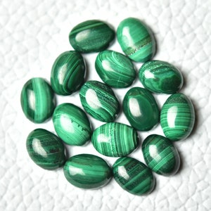 May include: A collection of oval-shaped malachite gemstones, each with a unique green and white pattern. The stones are smooth and polished, with a glossy finish.