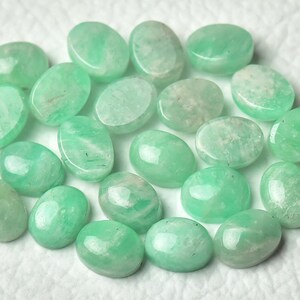 Peut inclure: Une collection de 18 pierres pr&eacute;cieuses vertes de forme ovale. Les pierres sont lisses et polies, de couleur vert clair.