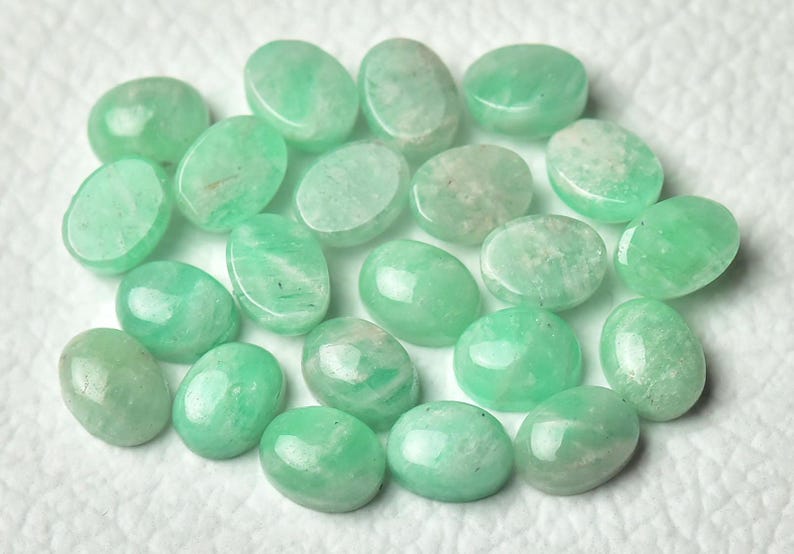 Peut inclure: Une collection de 18 pierres pr&eacute;cieuses vertes de forme ovale. Les pierres sont lisses et polies, de couleur vert clair.