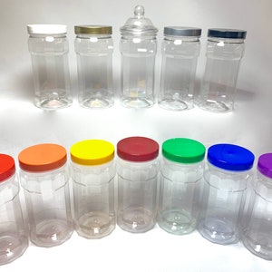 May include: A set of 11 clear plastic jars with various coloured lids. The lids are red, orange, yellow, green, blue, purple, and silver. The jars are all the same size and shape, and they are arranged in two rows.