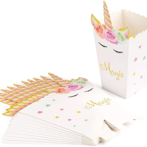 May include: A set of 10 white favour boxes with a unicorn design. The boxes have a pink, yellow and blue floral pattern with gold glitter accents. The boxes are decorated with the word "Magic" in gold glitter lettering.