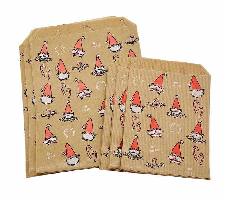 K&ouml;nnte beinhalten: Ein Set aus hellbraunen Papiert&uuml;ten mit einem wiederkehrenden Muster aus Weihnachtsmannfiguren mit roten M&uuml;tzen, Zuckerstangen und Texten wie Naughty or Nice, Joy to All und Ho! Ho! Ho! Die T&uuml;ten weisen eine vertikal gerippte Textur auf.