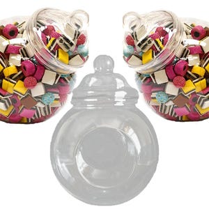 May include: Three clear glass candy jars with lids. Two jars are filled with colourful candy, and one jar is empty.