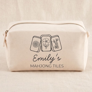 Könnte beinhalten: Eine beigefarbene Reißverschlusstasche aus Segeltuch mit einer schwarzen Strichgrafik von drei Mahjong-Steinen mit Blumen- und Bambusmotiven. Unter den Steinen steht der Text Emily's MAHJONG TILES in einer Kombination aus Schreib- und Druckschrift.