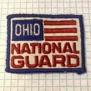 May include: Embroidered patch featuring the Ohio state flag design with the words "OHIO" and "NATIONAL GUARD" in white and red thread. The patch has a blue border and is rectangular in shape.