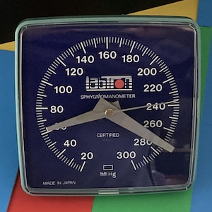 May include: A square Labtron sphygmomanometer gauge with a dark blue face, white numerical markings from 20 to 300, and two silver needles. The device features the text "CERTIFIED" and "MADE IN JAPAN" printed on the face in white lettering.