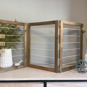 May include: A three-panel wooden room divider with white string strung across each panel. The divider is decorated with a potted plant, a small bird figurine, and a decorative wheel.