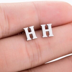 May include: A pair of silver initial earrings with the letter "H" on each earring.