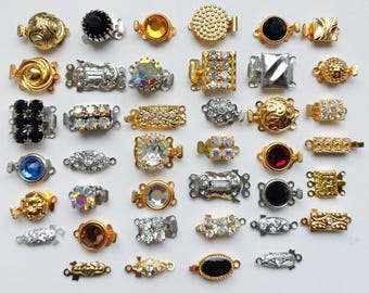 May include: A collection of various jewelry clasps in gold, silver, and mixed metal tones. The clasps feature a variety of designs, including round, oval, and rectangular shapes, adorned with rhinestones, crystals, and other decorative elements.