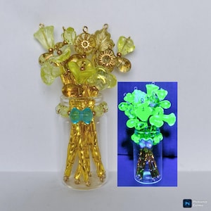 Puede incluir: Una botella de vidrio con un ramo de flores de cuentas amarillas y verdes. La botella tiene un lazo turquesa y cuentas doradas. Una imagen más pequeña muestra las flores brillando en verde.