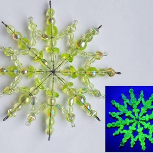 以下が含まれることがあります： ガラスビーズでできた緑色の雪の結晶のオーナメント。ブラックライトの下で光ります。