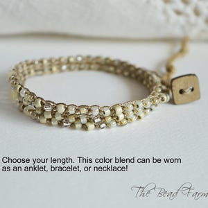 May include: Beaded bracelet in neutral tones with a wooden button closure. The bracelet is made of small, round beads in shades of cream, beige, and silver. The text says, "Choose your length. This color blend can be worn as an anklet, bracelet, or necklace!"