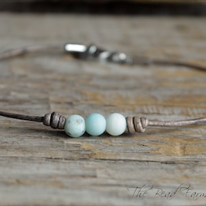 May include: A simple leather bracelet with three light blue and white gemstone beads.