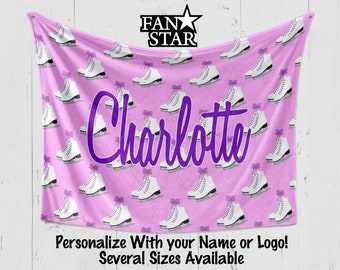 May include: Pink fleece blanket with a white ice skate pattern and the name "Charlotte" in purple text. The blanket is personalized with a name or logo and is available in several sizes. The text "FAN STAR" is in the top center of the blanket.