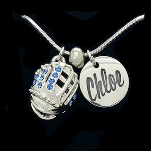 May include: Silver necklace with a blue rhinestone softball glove charm and a round silver tag with the name "Chloe" engraved on it.