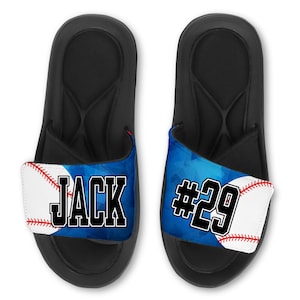May include: A pair of black slides with a blue and white baseball-themed strap. The strap features a baseball with red stitching and the text "JACK #29".