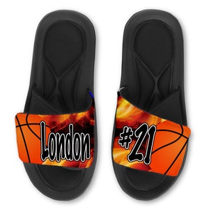 May include: Pair of black slide sandals with a basketball-themed strap. The strap features a basketball with flames and the text "London #21".