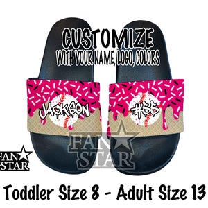 May include: Black slide sandals with a baseball theme. The sandals feature a pink and white sprinkle design with a baseball graphic. The text "Jackson" and "#55" are displayed on the sandals. The sandals are customizable with your name, logo, and colors.