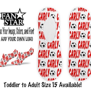 Puede incluir: Un par de calcetines blancos sin talón con un patrón de balón de fútbol rojo y blanco. Los calcetines tienen el nombre "Carly" repetido. El texto "Toddler to Adult Size 15 Available!" está en la parte inferior de la imagen.