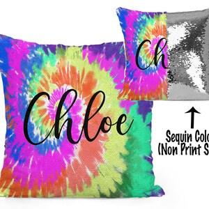 May include: A reversible sequin pillow with a tie-dye pattern on one side and silver sequins on the other. The tie-dye side features the name "Chloe" in black script.