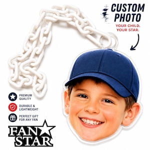 May include: A custom photo acrylic ornament featuring a smiling child wearing a blue baseball cap, attached to a white plastic chain. The text reads CUSTOM PHOTO YOUR CHILD. YOUR STAR. PREMIUM QUALITY DURABLE & LIGHTWEIGHT FAN STAR.