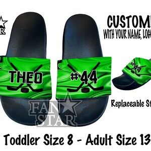 May include: Green and black personalized slides with a hockey stick and puck design. The slides are customizable with a name and number. The text on the slides reads "THEO #44".