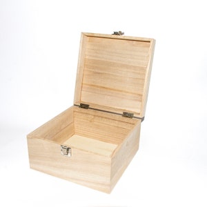 May include: An empty wooden box with a hinged lid and a metal latch. The box is made of light-colored wood and has a natural finish.