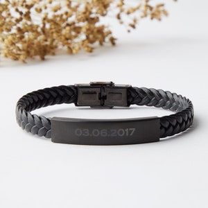 May include: Black leather braided bracelet with a black metal plate engraved with the date "03.06.2017".