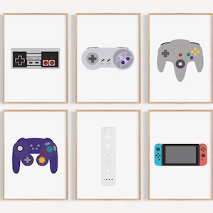Puede incluir: Seis impresiones enmarcadas de diferentes mandos y consolas de videojuegos. Las impresiones son sobre fondo blanco con un marco de madera claro. Los mandos incluyen un mando de Nintendo Entertainment System, un mando de Super Nintendo Entertainment System, un mando de Nintendo 64, un mando de GameCube, un mando de Wii y una Nintendo Switch.