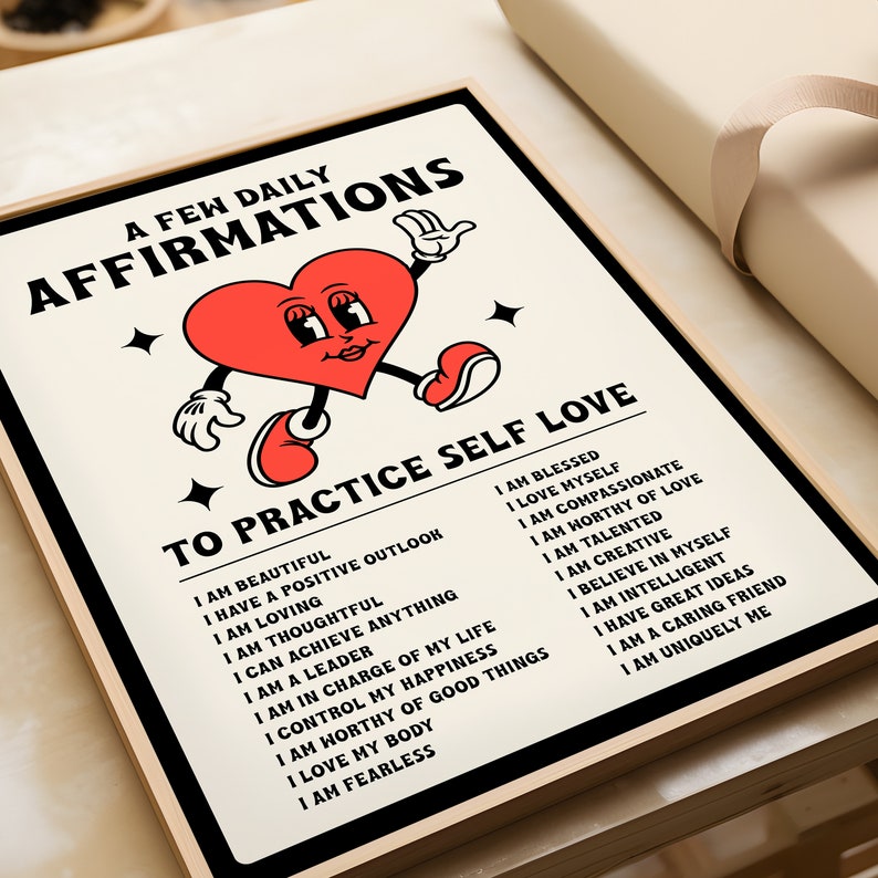 May include: A framed print with the words "A Few Daily Affirmations" and "To Practice Self Love." The print features a cartoon heart character with arms and legs. The affirmations are listed in black text on a cream background.