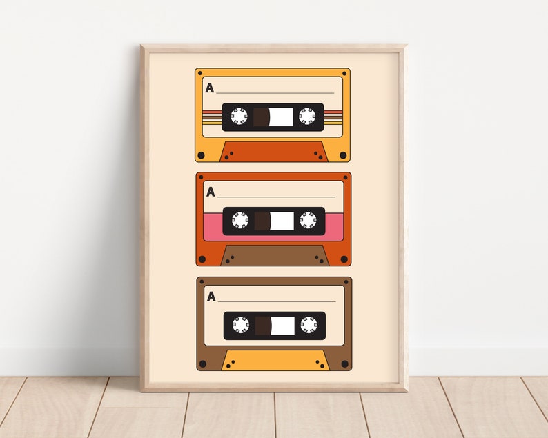 May include: A framed print with three vintage cassette tapes in a retro style. The tapes are stacked vertically and have a yellow, orange, and brown color scheme. The tapes have the letter "A" printed on them.