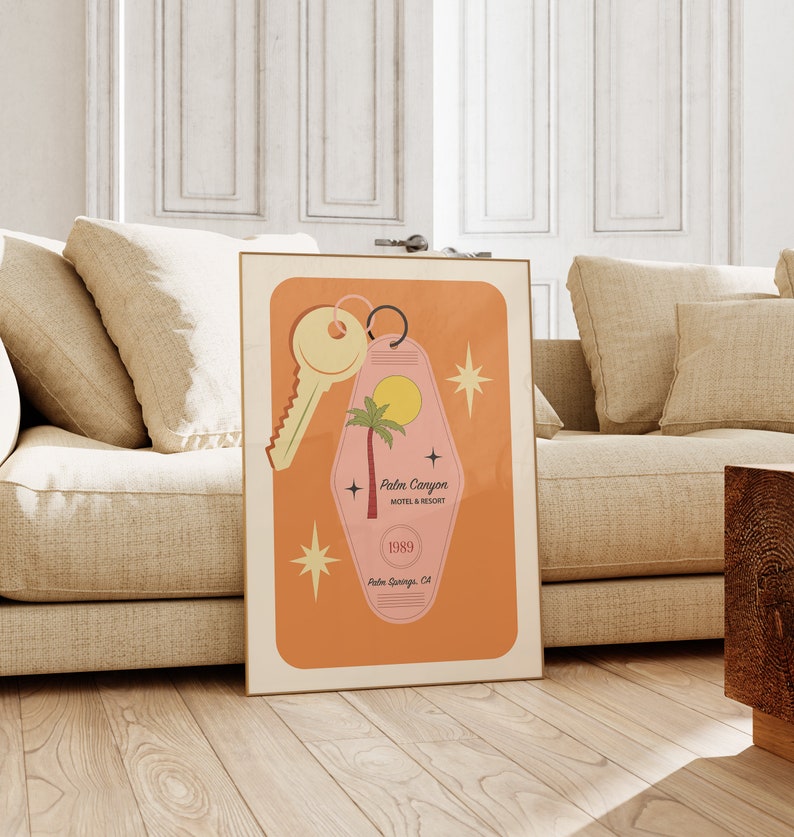 May include: A retro-style motel key tag with a pink background and a palm tree silhouette. The tag reads "Palm Canyon Motel & Resort" and "1989 Palm Springs, CA". A gold key is attached to the tag.