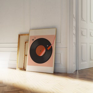 May include: A framed print of a black vinyl record with a pink background. The record has a red and orange stripe on the label. The print has a gold frame.
