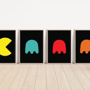 K&ouml;nnte beinhalten: Vier gerahmte Kunstdrucke mit Pac-Man und Geisterfiguren. Der Pac-Man-Druck ist gelb, und die Geister sind t&uuml;rkis, rot und orange. Jeder Druck hat einen schwarzen Hintergrund und einen hellfarbigen Rahmen.