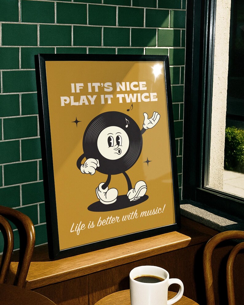 Puede incluir: Un p&oacute;ster enmarcado con un personaje de disco de vinilo de dibujos animados retro sobre un fondo amarillo mostaza. El texto dice "IF IT'S NICE PLAY IT TWICE" y "Life is better with music!". El p&oacute;ster se muestra en una repisa de madera.