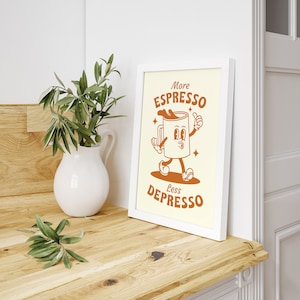 May include: A white framed print with a cartoon illustration of a coffee cup with legs and arms. The text on the print reads "More Espresso Less Depresso".