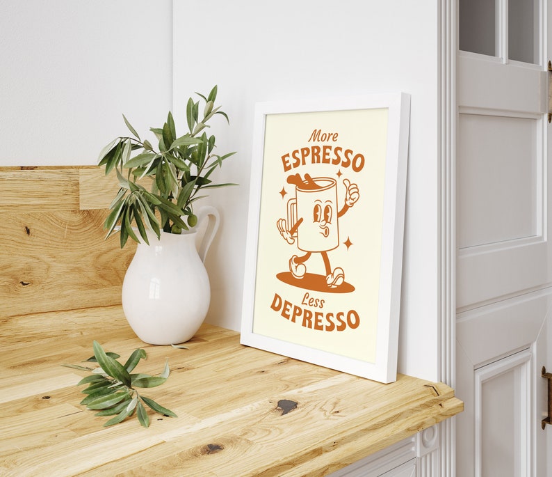 May include: A white framed print with a cartoon illustration of a coffee cup with legs and arms. The text on the print reads "More Espresso Less Depresso".