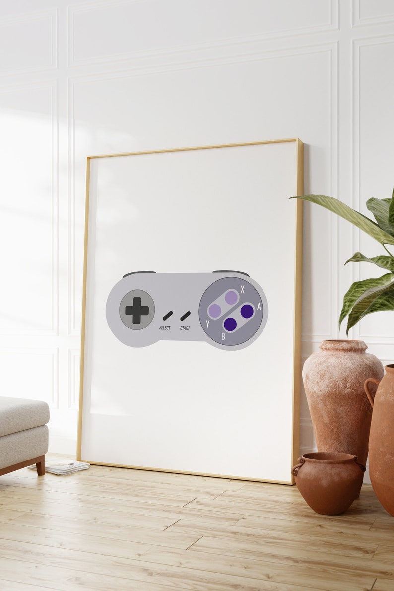 Puede incluir: Una impresi&oacute;n enmarcada de un mando de Super Nintendo gris y morado con las palabras "Select", "Start", "Y", "B", "X" y "A" impresas en &eacute;l.