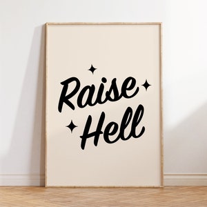 May include: A beige framed print with black text that reads "Raise Hell" with small stars on either side of the text.