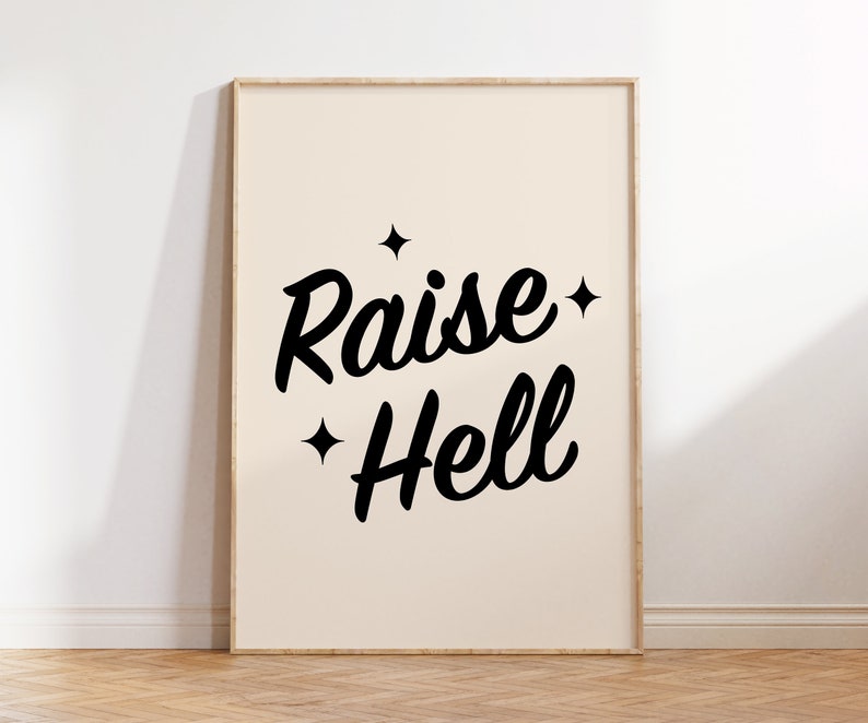 May include: A beige framed print with black text that reads "Raise Hell" with small stars on either side of the text.