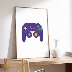 Puede incluir: Una impresi&oacute;n enmarcada de un mando de videojuego morado sobre un fondo blanco. El mando tiene un bot&oacute;n amarillo, rojo y azul.